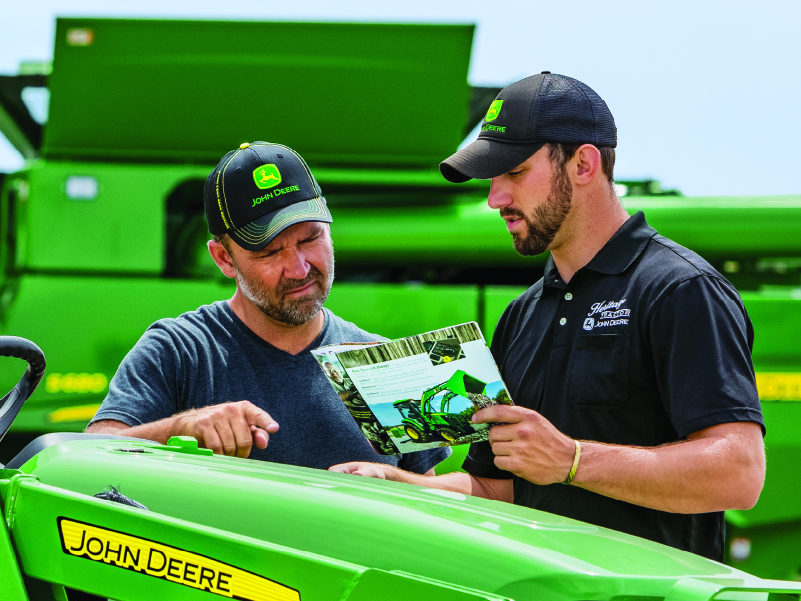 HEAVY AND FARM EQUIPMENT Salesman with customer discussing tractor